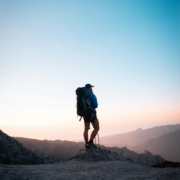 man in black jacket and blue denim shorts with black hiking backpack standing on mountain during