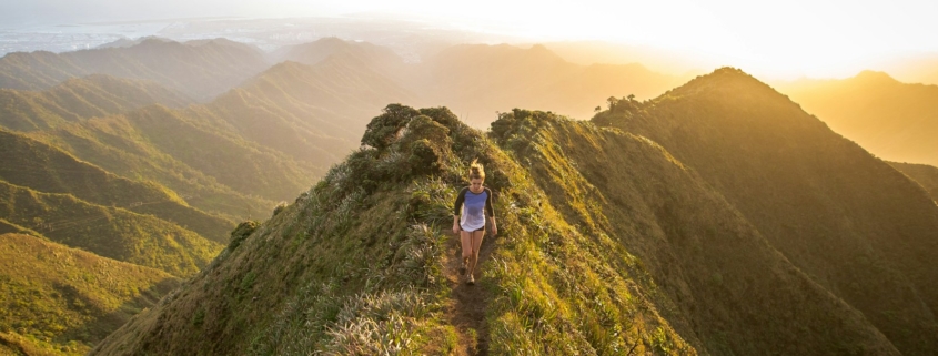 woman walking on pathway on top of hill at golden hour