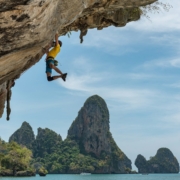 man climbing cliff beside beach